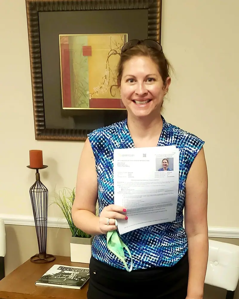 A smiling student holding her passing Alabama real estate exam score