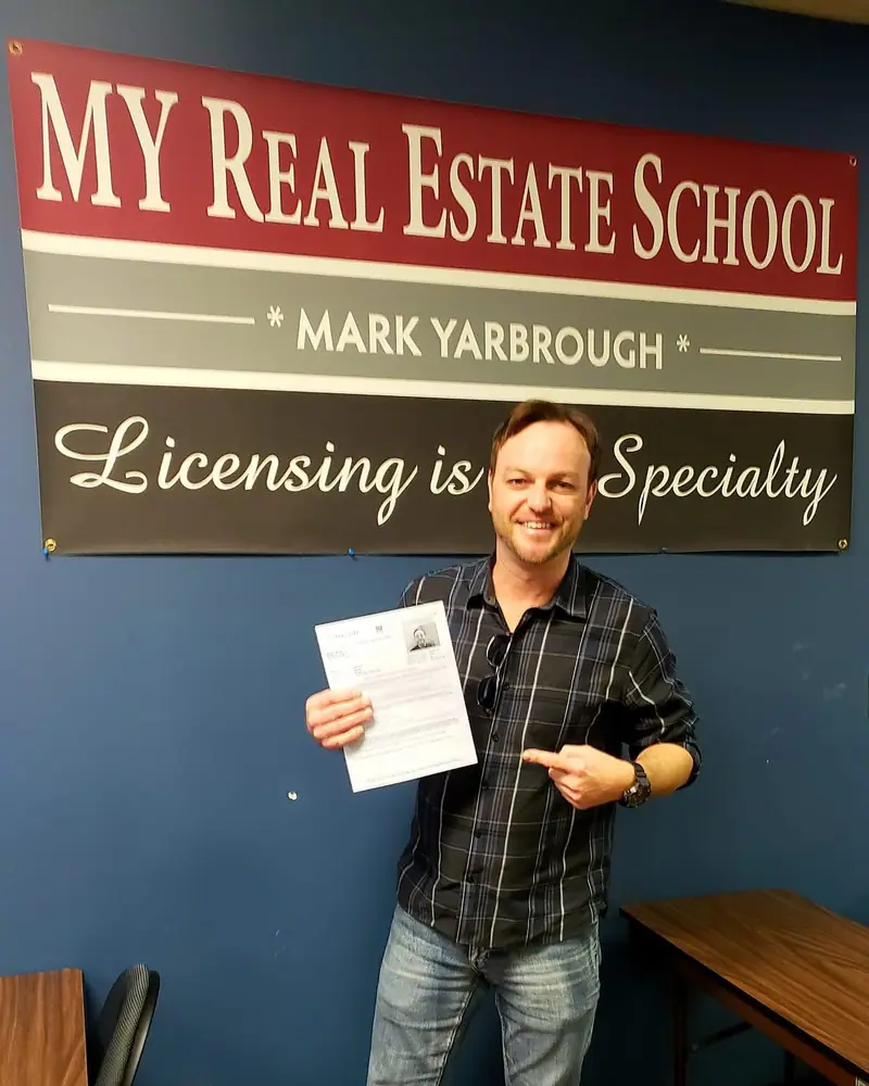 A student pointing to his passing real estate exam score