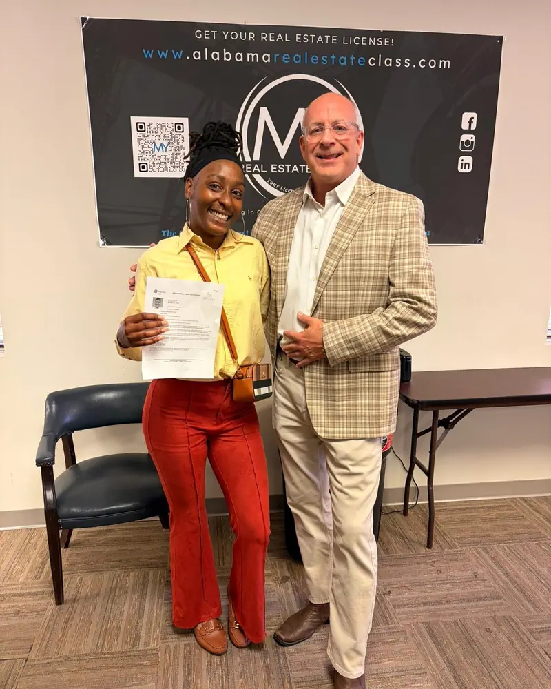 A new licensee with instructor Mark Yarbrough, holding her passing score